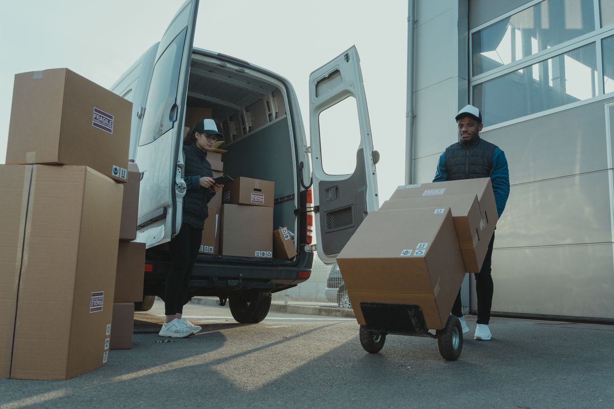 Courier operators loading and delivering packages from a delivery van